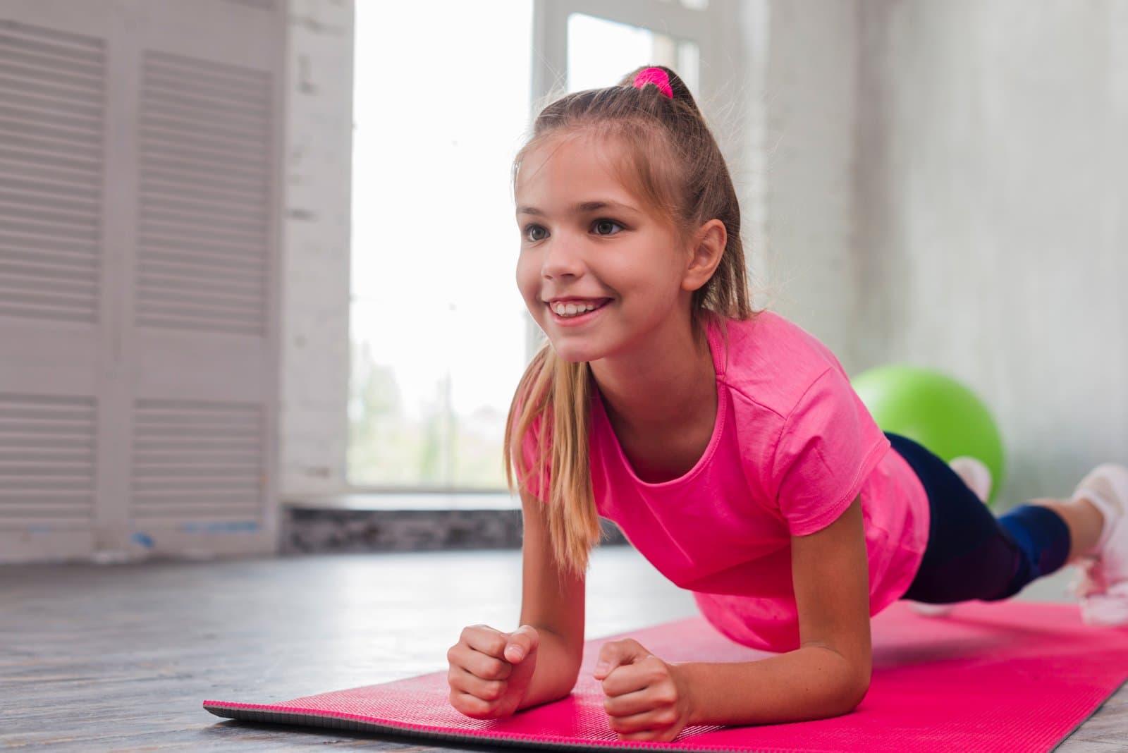 A imagem mostra uma garota jovem sorridente praticando um exercício físico